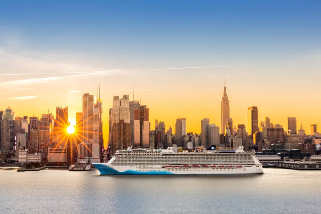 Großes Kreuzfahrtschiff auf dem Hudson River vor der Skyline New York Citys bei Sonnenaufgang
