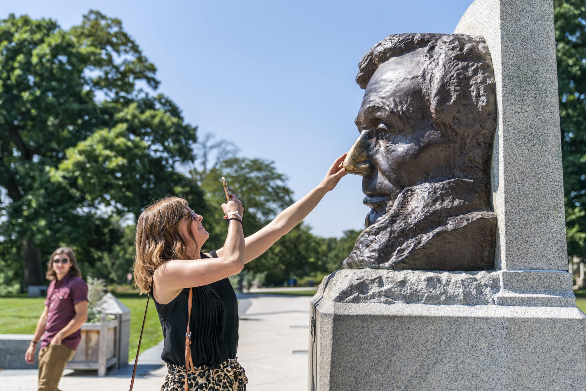 A woman takes a photo rubbing Abe's nose at the Lincoln Tomb