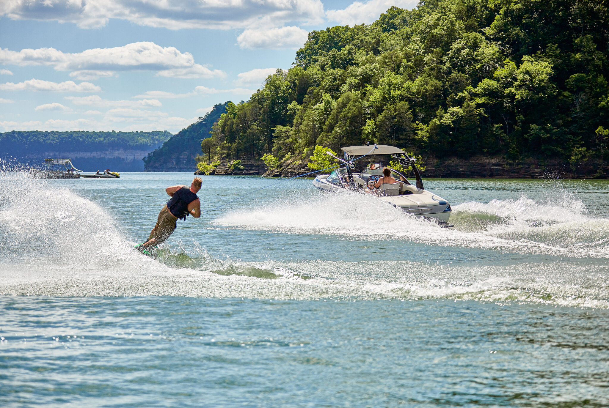 Mann fährt auf einem Wakeboard hinter einem Motorboot