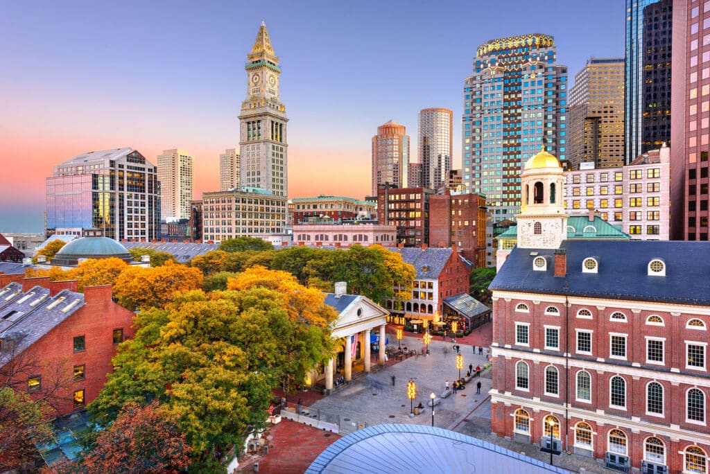 Die Skyline von Boston mit dem historischen Quincy Market und dem charakteristischen Uhrenturm bei Sonnenuntergang.
