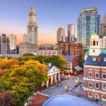 Die Skyline von Boston mit dem historischen Quincy Market und dem charakteristischen Uhrenturm bei Sonnenuntergang.