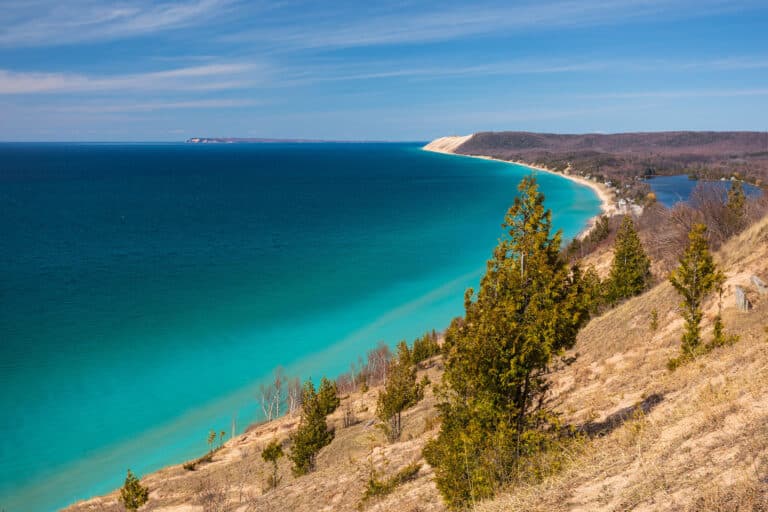 Panoramablick auf den Michigansee mit türkisfarbenem Wasser und einer Sanddüne am Ufer.