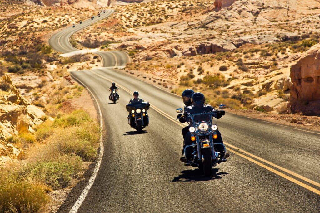 Motorradfahrer fahren auf einer sich windenden Straße durch goldfarbene Berglandschaft in Arizona