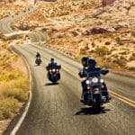 Motorradfahrer fahren auf einer sich windenden Straße durch goldfarbene Berglandschaft in Arizona