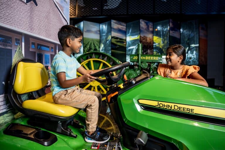 Ein Kind sitzt auf einem modernen Traktor von John Deere in deren Besucherzentrum und Museum in Moline, Illinois
